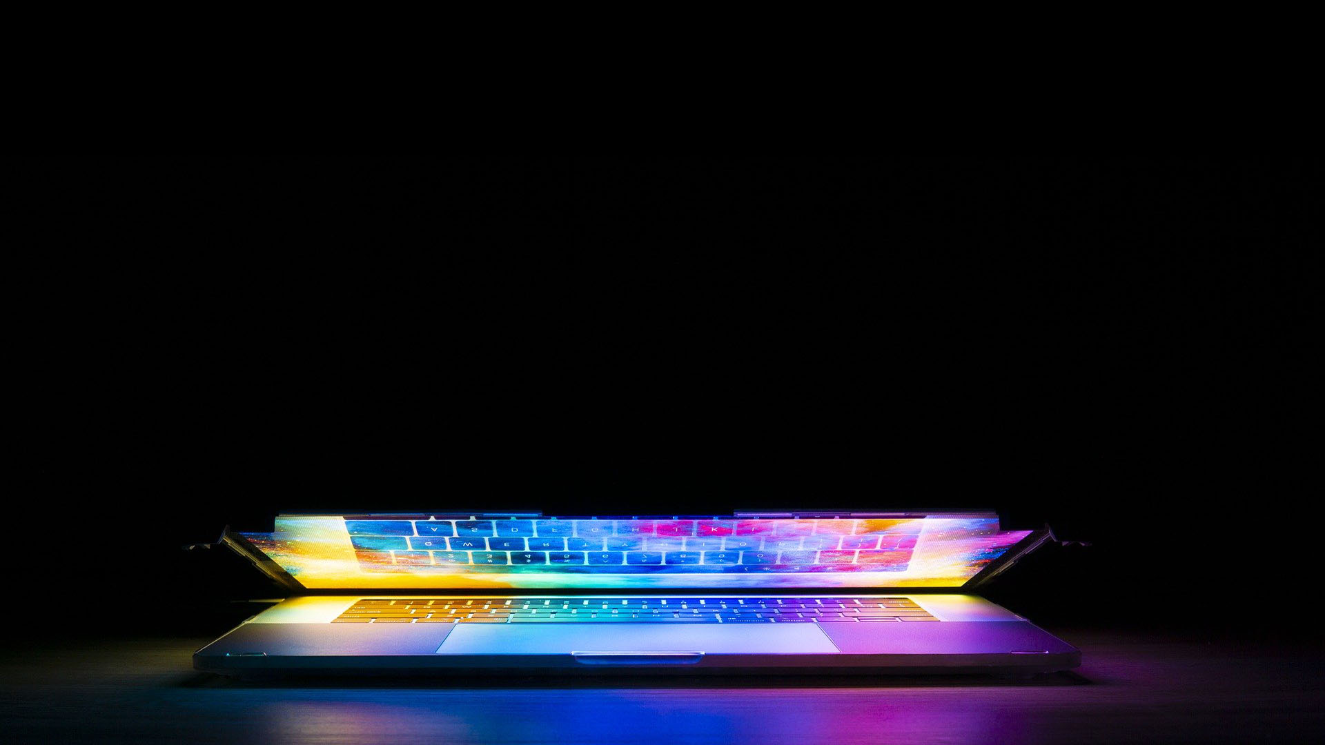 A laptop glowing with a variety of colours.