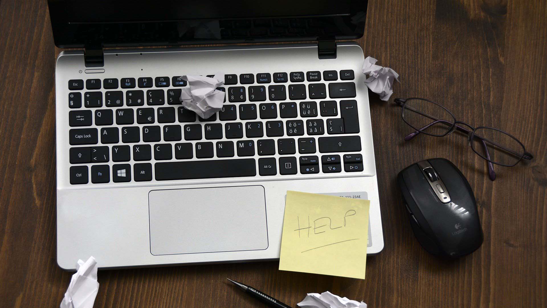 A laptop with 'Help' written on a post-it note which is stuck to the laptop.